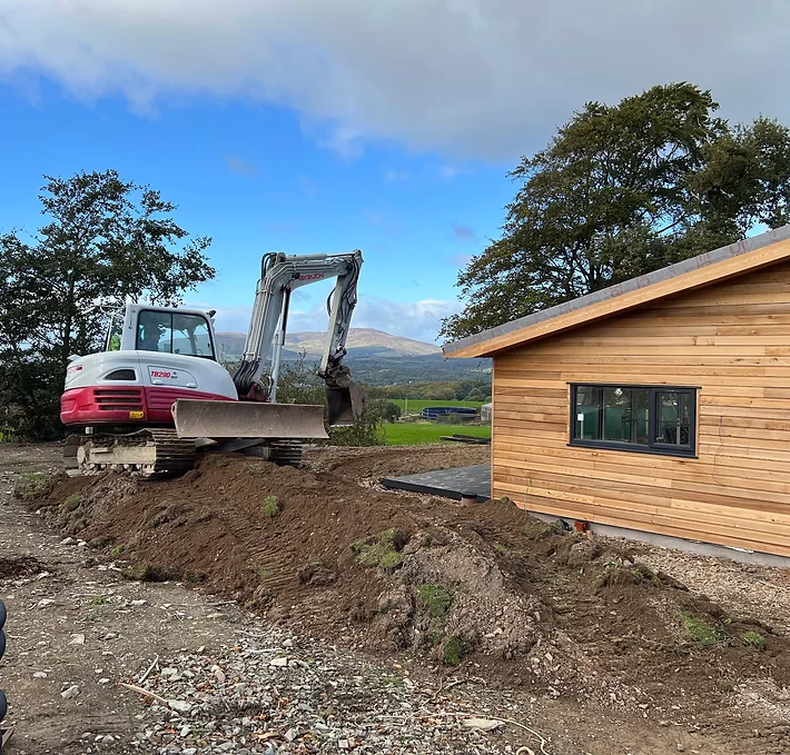 Digger positioned outside the lodge, diligently sculpting the landscape with precision and care, laying the groundwork for an outdoor oasis where guests can immerse themselves in the beauty of nature's craftsmanship