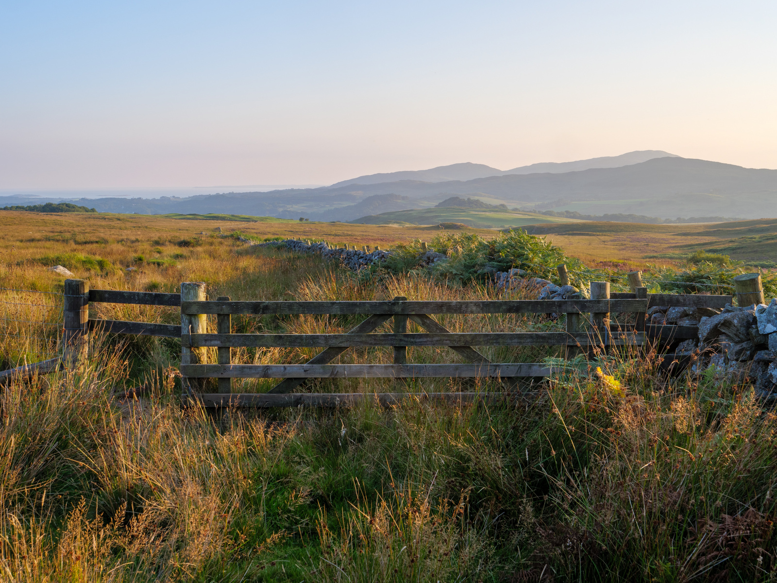 A traditional gate stands proudly amidst the breathtaking Scottish landscape, its weathered wooden frame a timeless symbol of entry into the majestic wilderness beyond, where rolling hills, lush greenery, and rugged beauty await exploration and discovery