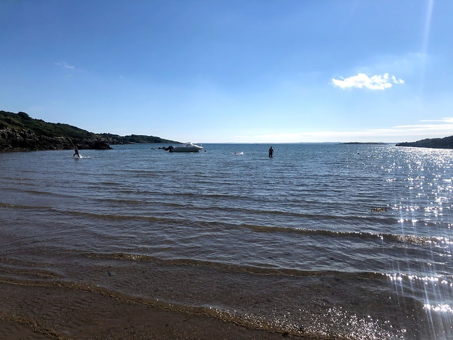 The beach at Carrick with the sea coming in and a speedboat in the middle